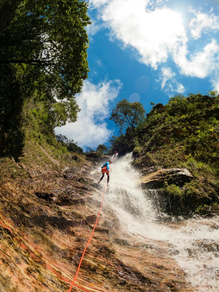 Thrilling waterfall climbing adventure with vivid natural scenery and bright blue skies.