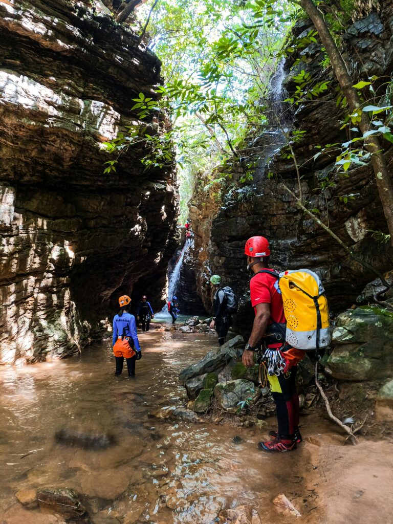 Thrill-seekers canyoning in a spectacular rocky stream surrounded by lush vegetation.